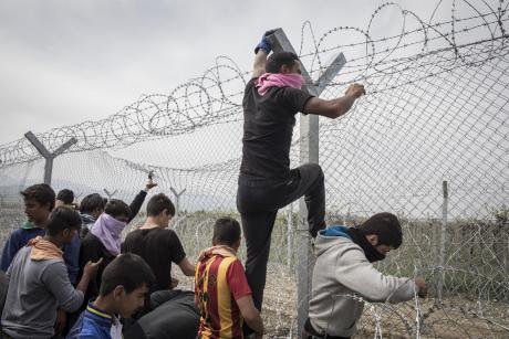 Men try to climb a fence at the Macedonia-Greece border in 2016.