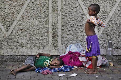 A homeless street child wears a shirt as another sleeps on a pavement in Kolkata, India. Credit: Bikas Das/AP/Press Associatio