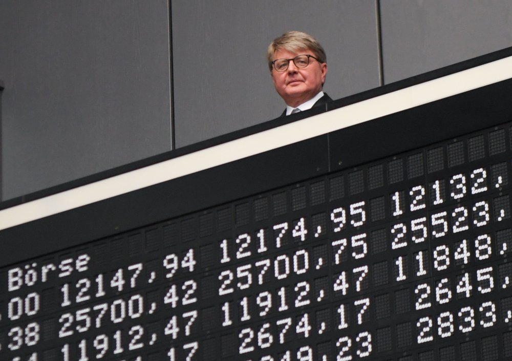 A man appearing above a stock exchange display board