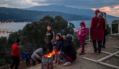 Refugees warm themselves by a campfire in a refugee camp on Samos, Greece.