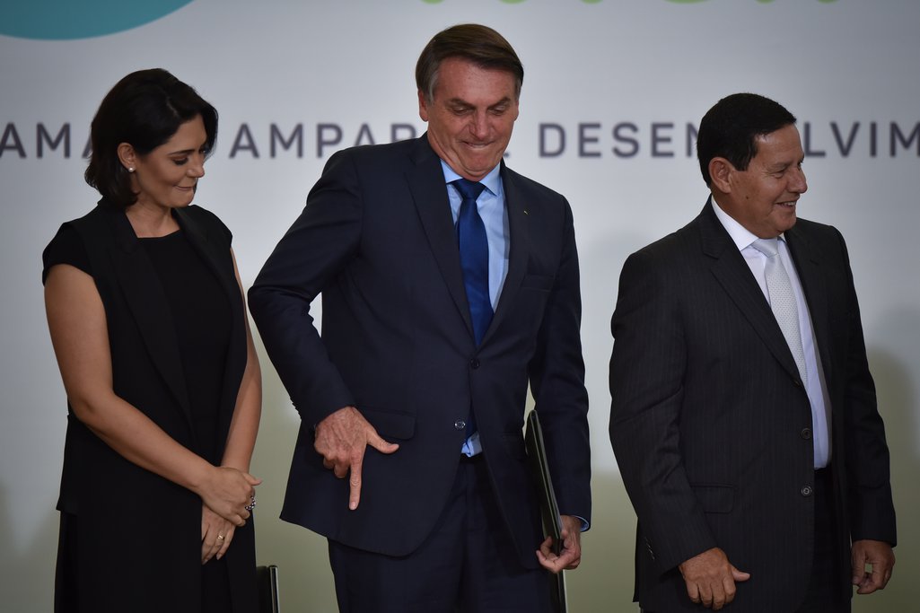 A primeira dama Michelle Bolsonaro e o vice-presidente Hamilton Mourão junto ao presidente brasileiro Jair Bolsonaro enquanto faz uma arminha com a mão no Palácio Planalto, em Brasília, Brasil, em março de 2020.
