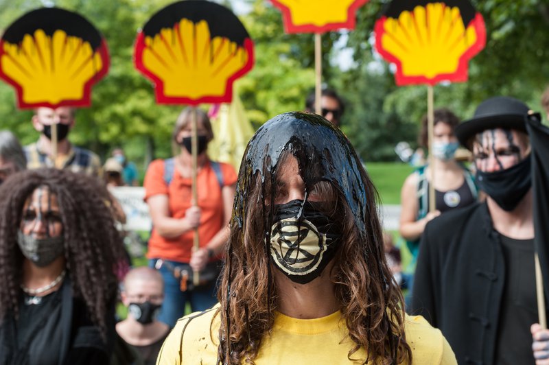Ativistas da Extinction Rebellion cobertos de tinta preta durante um protesto em frente aos escritórios corporativos da empresa petrolífera Shell exigindo o fim da extração de combustíveis fósseis