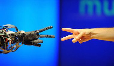 A robot faces off against a human in a game of 'rock paper scissors' at the Science Museum, London.