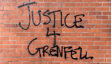 Graffiti on a red brick wall. Reads Justice 4 Grenfell.