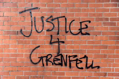 Graffiti on a red brick wall. Reads Justice 4 Grenfell.