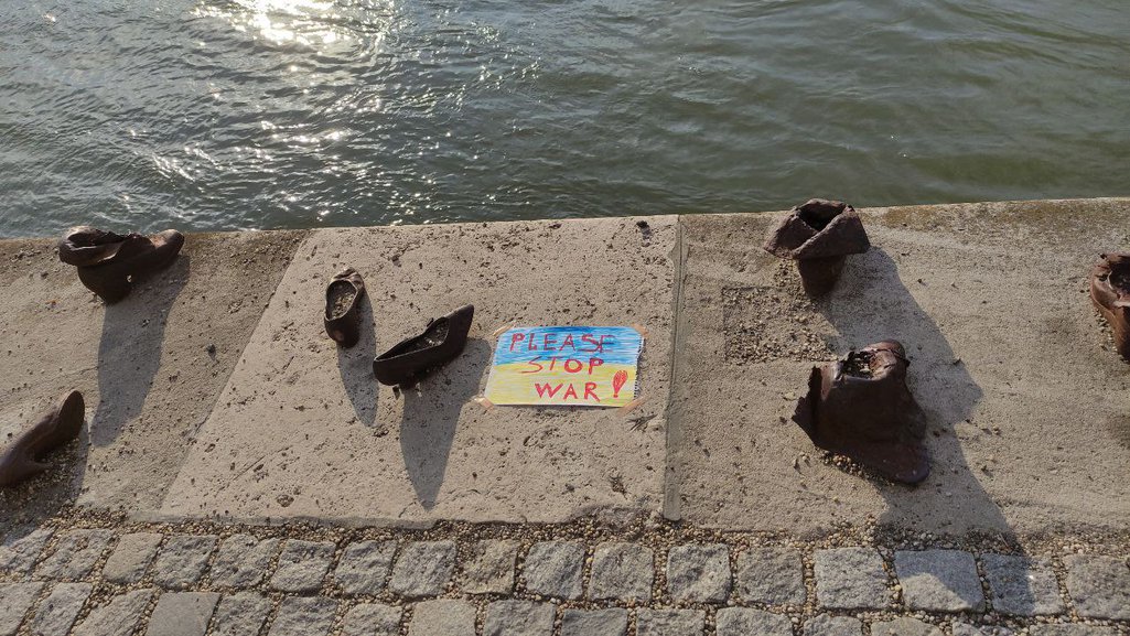 A placard bearing the Ukrainian flag rests on the ground next to Budapest's Holocaust memorial by the Danube