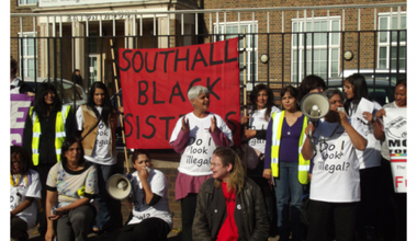 Women demonstrating with a Southall Black Sisters banner and megaphone
