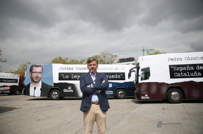 Ignacio Arsuaga in front of buses carrying ads against Vox’s opponents