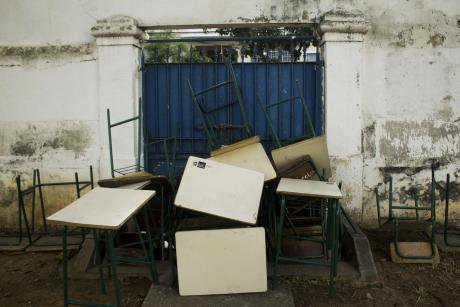 Desks and chairs piled up in front of the inside of the school gates, as a barricade