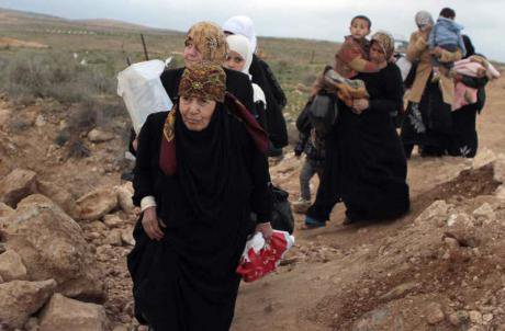 Seven women walking in a line, some with children on their backs