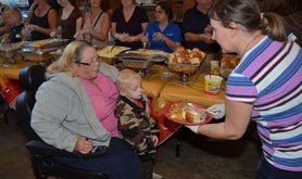 Woman handing a woman and child a plate of food.