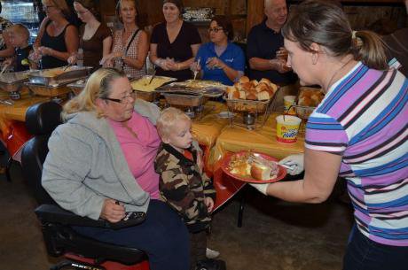 Woman handing a woman and child a plate of food.