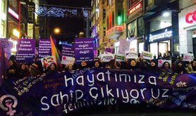 Women march at night with a banner
