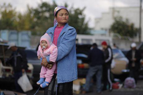 A woman holds her baby at a street market in Tokmok, Kyrgyzstan. Credit: Alexander Zemlianichenko/AP/Press Association Images