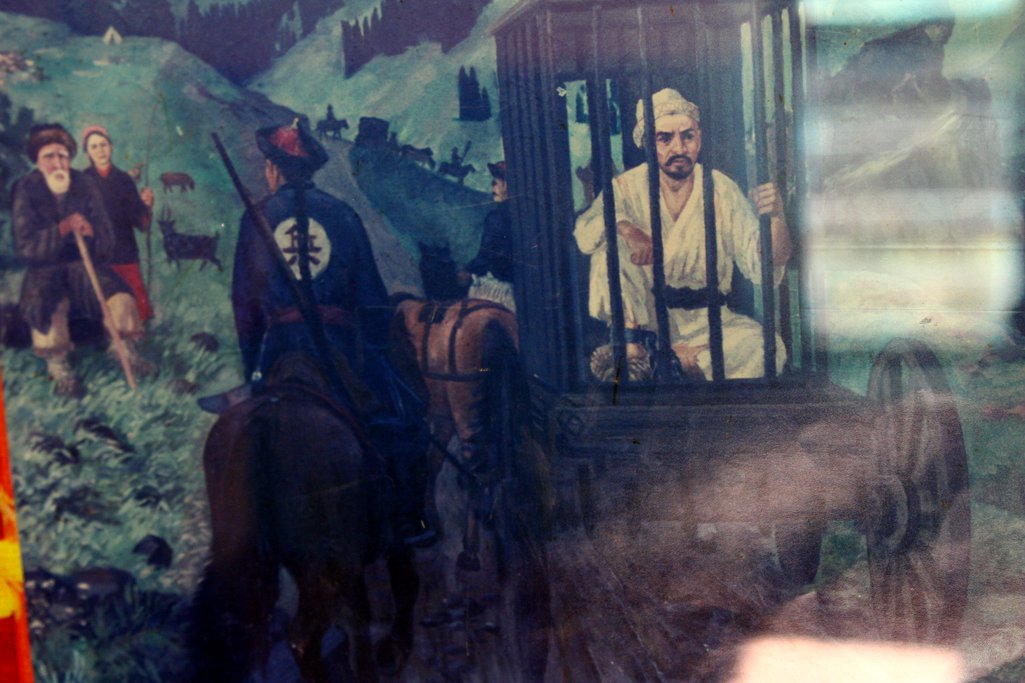 Painting of man in a cage being carried on the back of a horse-drawn cart