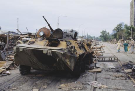 A burnt out armoured vehicle from the Abkhaz-Georgian War in 1994. Civilians walk by