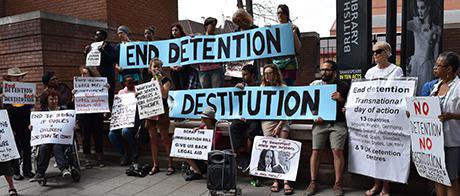 Group of people holding banners and posters, which call for the of end destitution and detention.