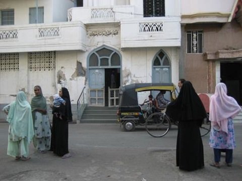 Women chatting on a street as traffic goes by