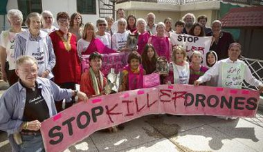 Men and Women surround a pink 'Stop Killer Drones' banner