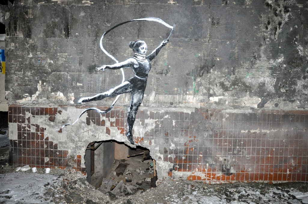 The Banksy shows a child spinning on top of a circle hole in the wall of a ruined building