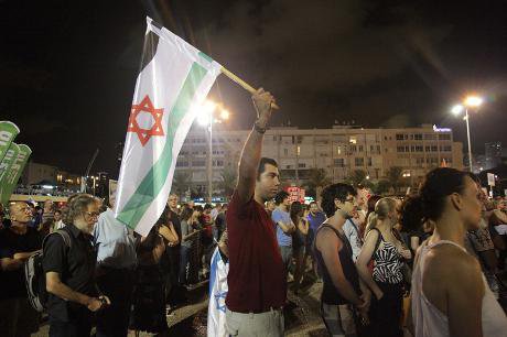 Peace demonstrator in Tel Aviv holds up Israeli flag in Palestinian colours