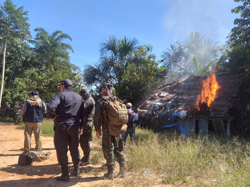 Os homens assistem como uma pequena casa queimando durante uma intervenção de erradicação do governo regional