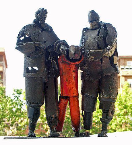 Protest sculpture in metal against Guantanamo, with stylised camp guards and helpless detainee