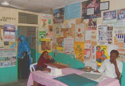 Photo of room covered with health posters with two people sitting at a table.