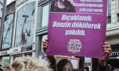 Woman holding a placard with an image of a young woman alongside Turkish text