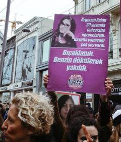 Woman holding a placard with an image of a young woman alongside Turkish text