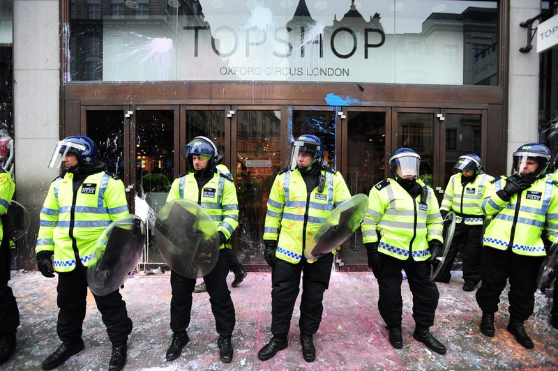 Police guard a paint spattered Top Shop during anti-cuts protest