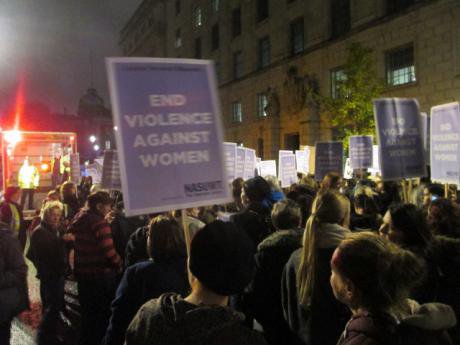 Women marching in the dark with an &#39;End Violence Against Women&#39; placard visible