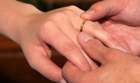 Man putting wedding ring on woman's finger