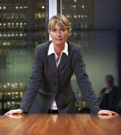 Business woman in board room, hands on table, staring out confidently