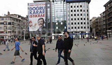 People walk by Turkish PM billboard.