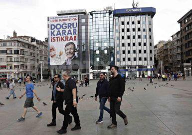 People walk by Turkish PM billboard.