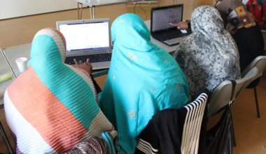 Three women sitting at computers, backs to camera
