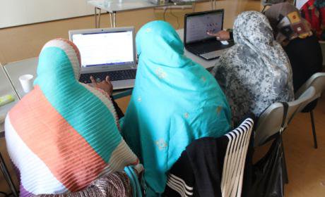 Three women sitting at computers, backs to camera