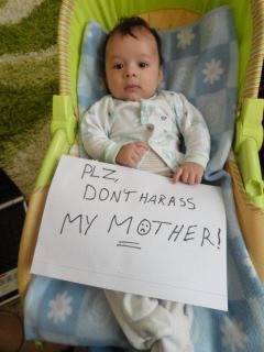 Baby holding a sign reading &#39;please don&#39;t harras my mother&#39;