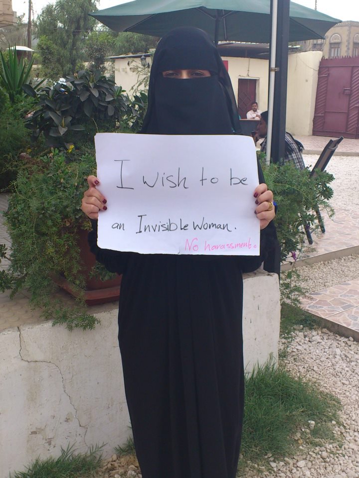 Woman in full niqab with sign reading: I want to be an invisible woman